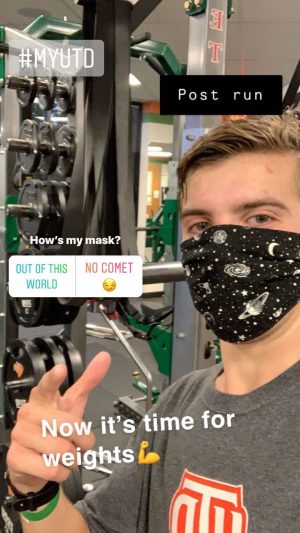 Trent in a weight room. He's wearing a UTD t-shirt and a black mask with print of stars, moons and and planets.