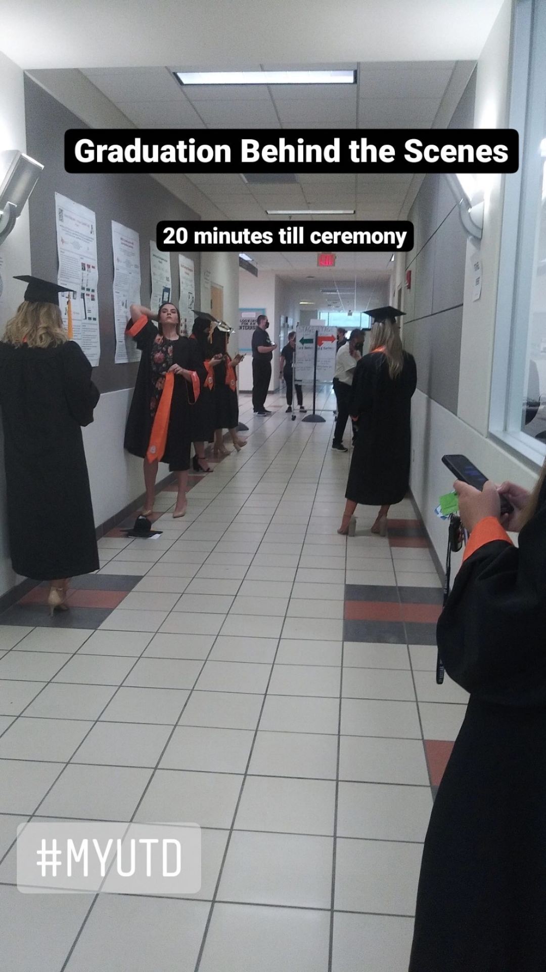 Graduation behind the scenes. Graduates in regalia line the hallway of the activity center.