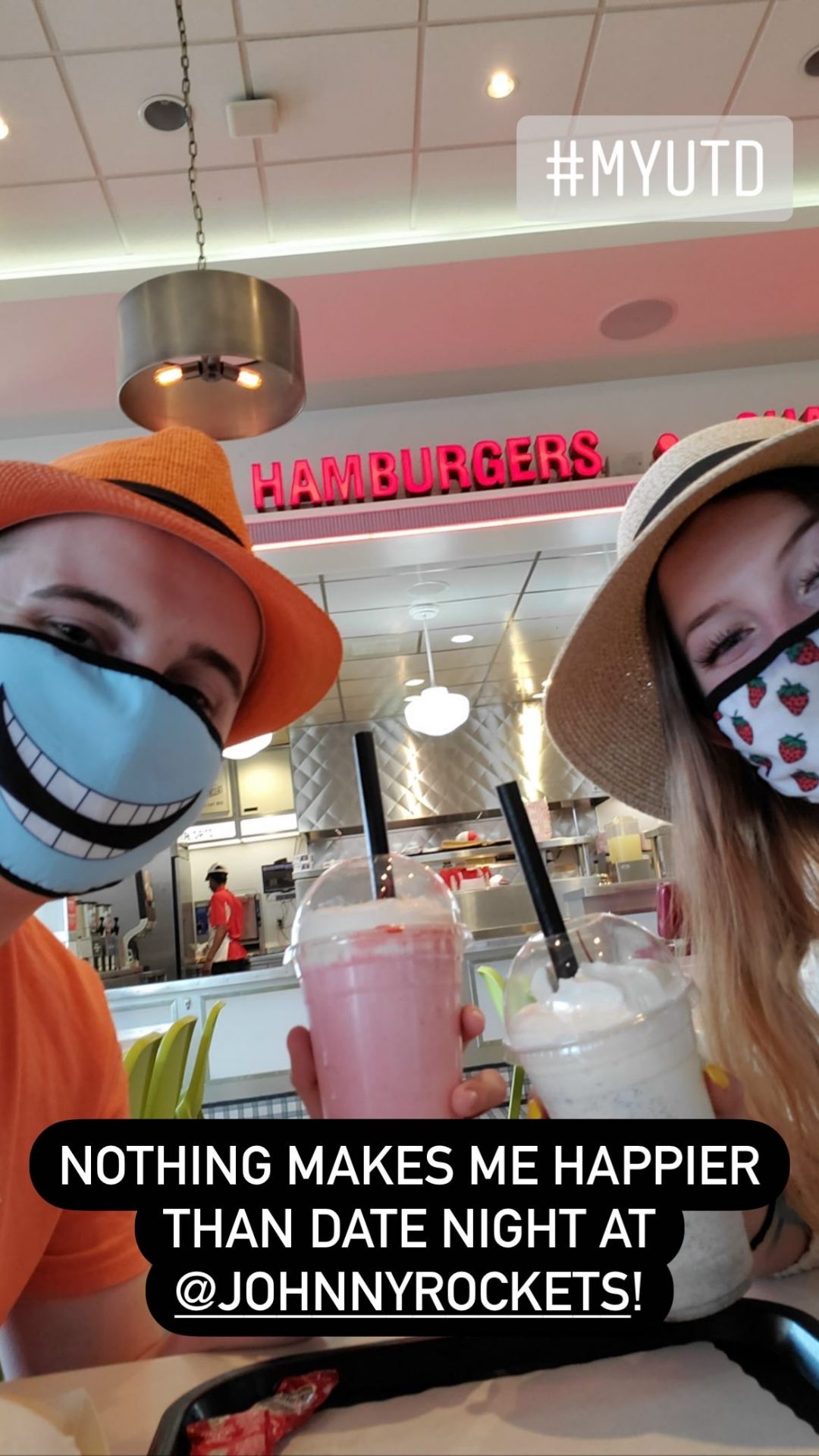 Troy and Troys date wearing hats and masks pose with milk shakes.