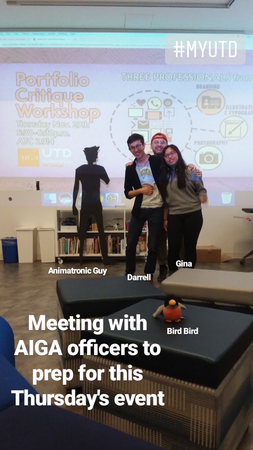 Three people standing close together in front of a presentation display that reads, Portfolio Critique Workshop. There is also a cutout of a person made of black paper. Bird figurine is present. 